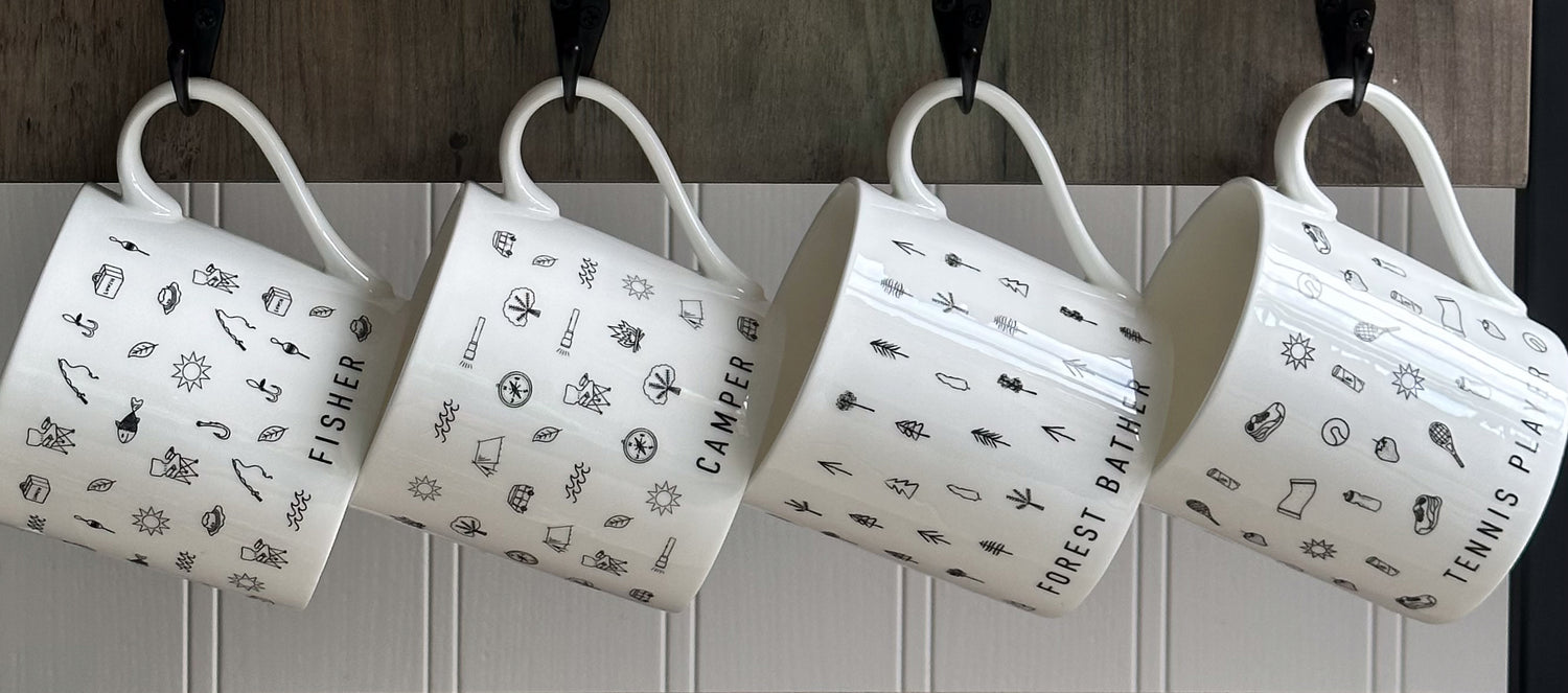 Four black and white mugs with hobbies based designs hanging from hooks