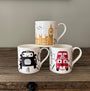 Three mugs with London-themed designs on a wooden surface.