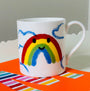White mug with a rainbow design on an orange surface