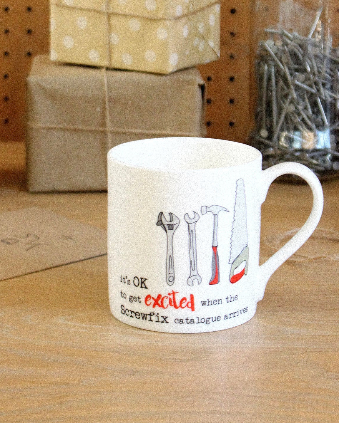 Mug with tool design and text on a wooden surface with gift boxes in the background