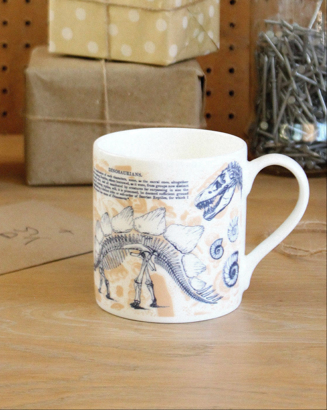 Mug with dinosaur design on a wooden surface with gift boxes in the background