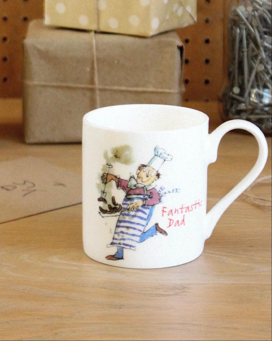 Mug with cartoon character and text on a wooden surface with gift boxes in the background